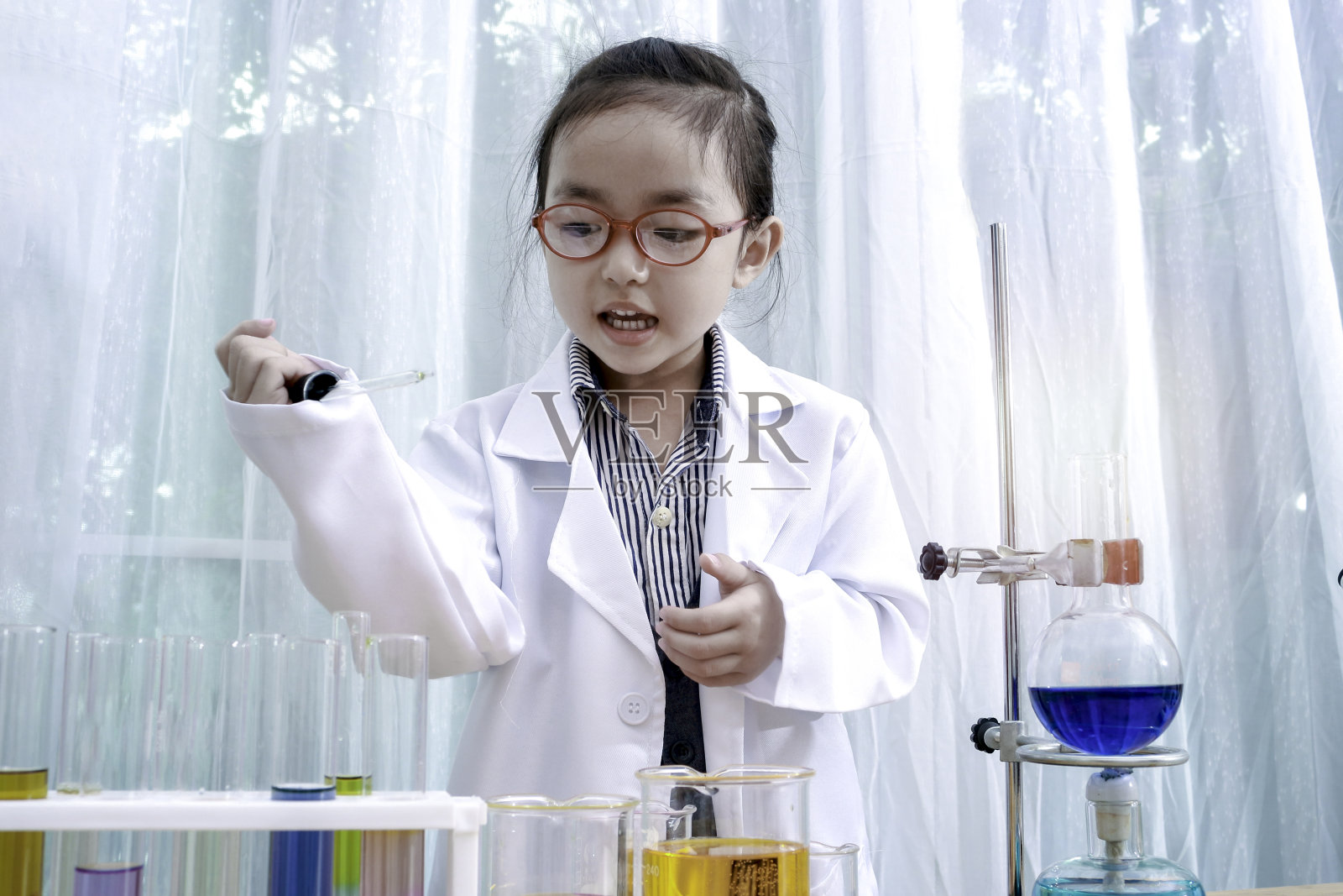 一个亚洲小女孩在实验室做实验。酷孩子学习化学科学，孩子假装是科学家，在实验室里玩得很开心。照片摄影图片
