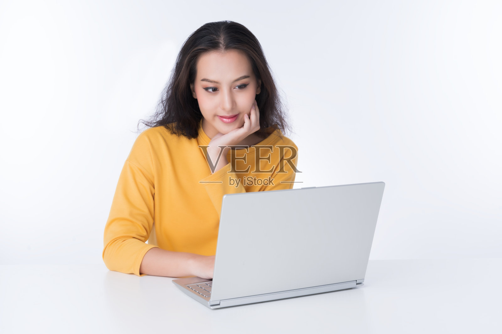 年轻的亚洲女人在笔记本电脑上工作，她穿着一件黄色毛衣，拍摄孤立的白色背景照片摄影图片