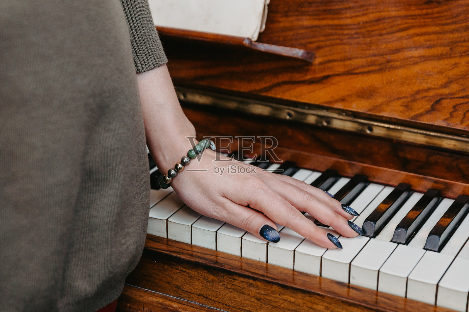 一位年轻女子的手放在一架钢琴的键上照片摄影图片