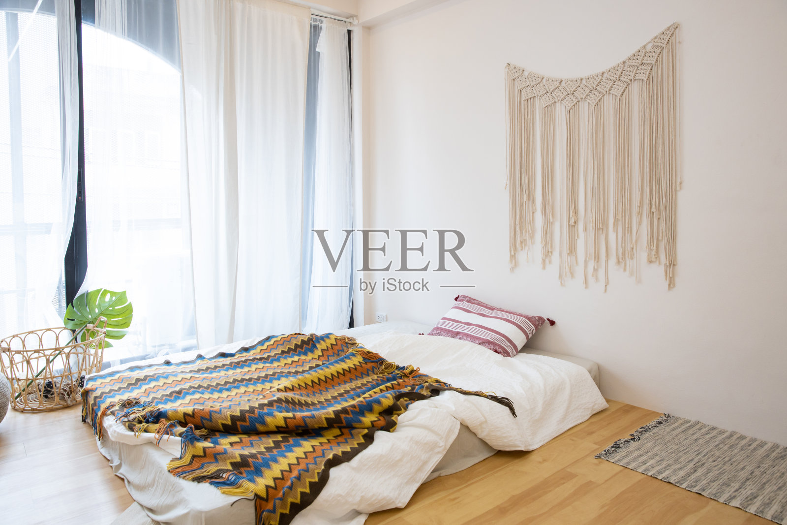 室内视图，未整理的凌乱的床在一个早晨的木地板上，有窗帘和阳光照片摄影图片