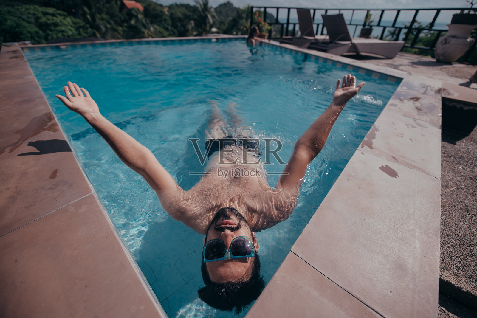 一个年轻英俊的男人在室外游泳池的肖像。泳池边长着胡子的帅哥照片摄影图片
