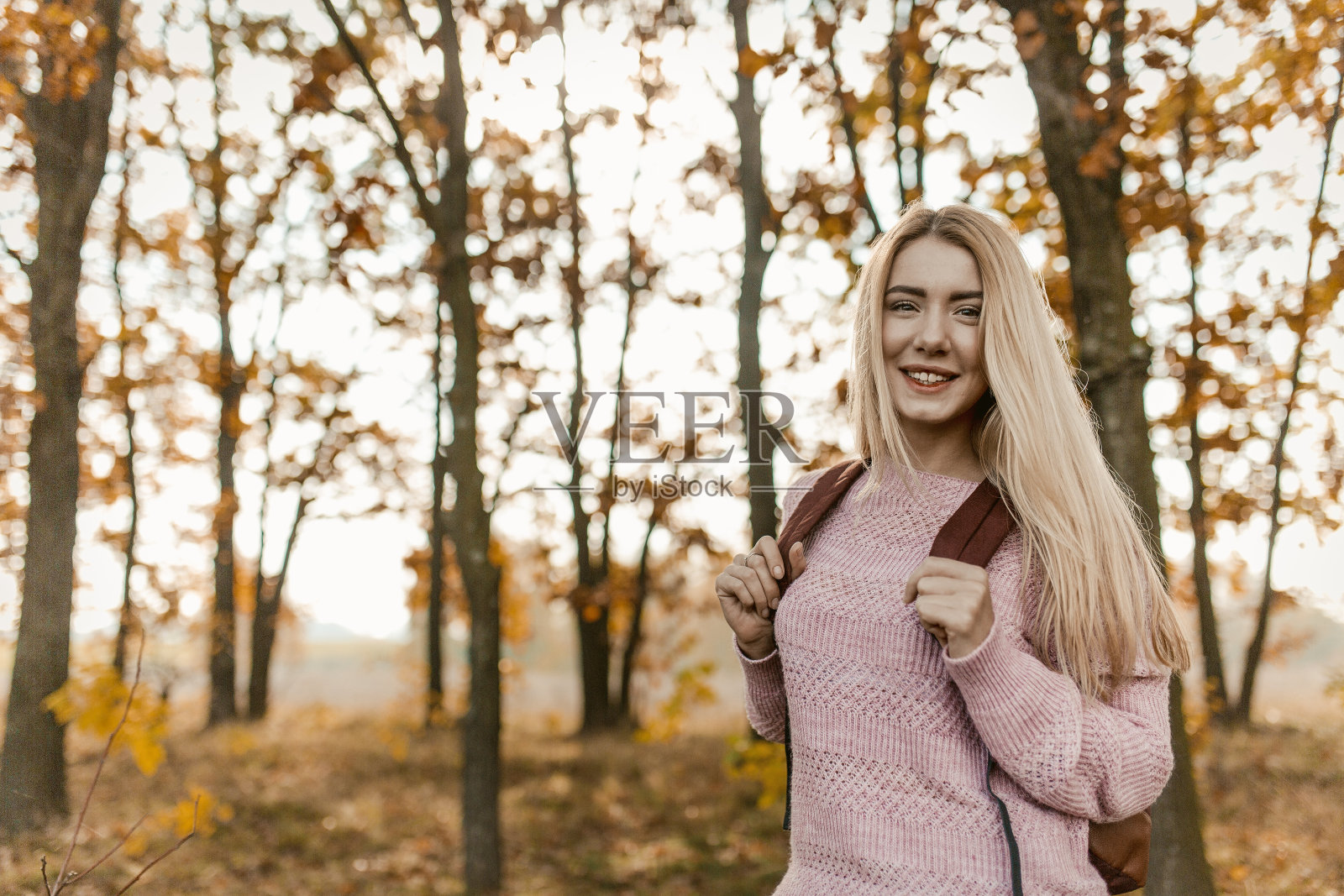 女金发旅行者在秋天的森林背后摆姿势照片摄影图片