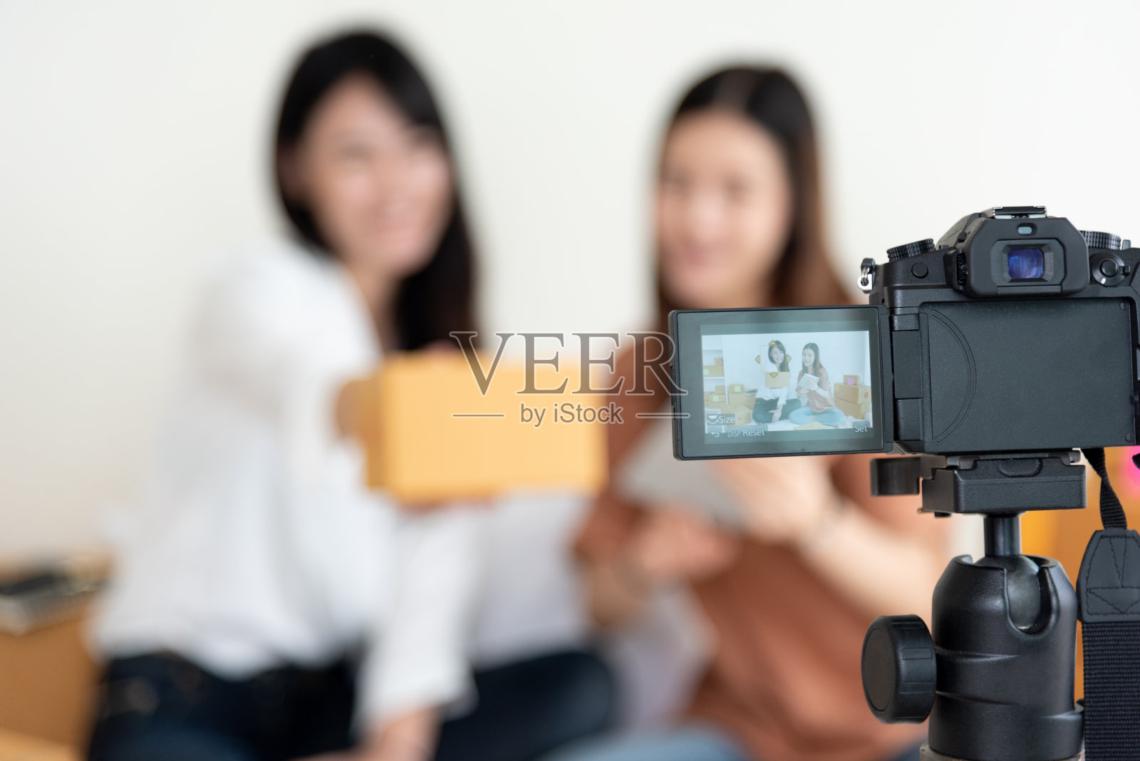 数码摄像机的特写镜头记录了两个女孩展示新产品广告。视频博客和影响者的概念。人们兼职工作和职业。使用现代科技的青少年照片摄影图片