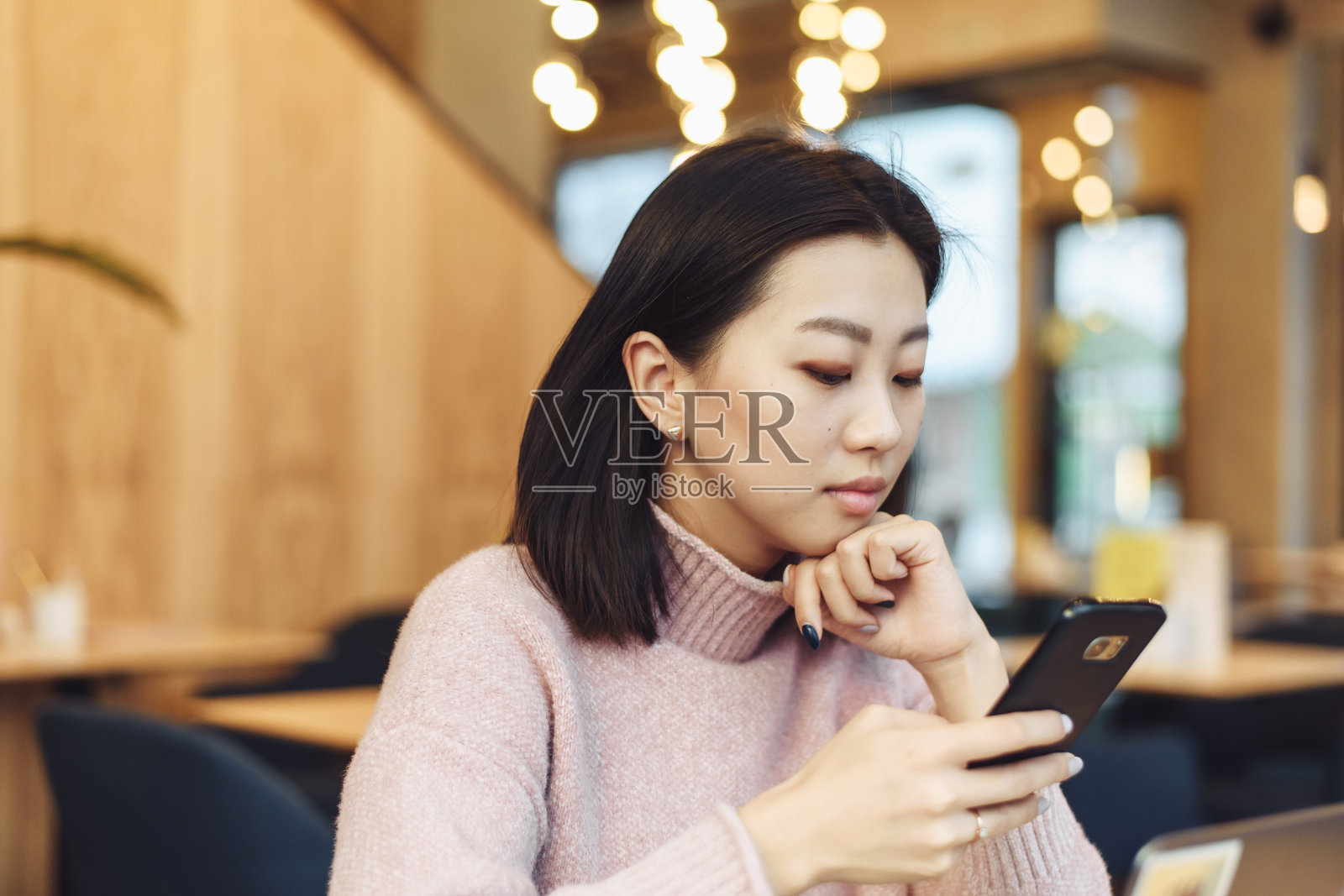 亚洲可爱的女孩爬上电话在咖啡店。一个漂亮的女人正在网上寻找信息或工作照片摄影图片