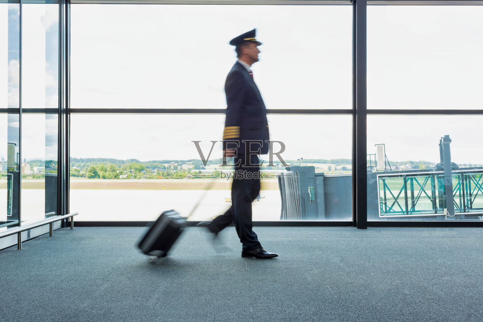 成熟的飞行员用黄色镜头光晕在机场行走的肖像照片摄影图片