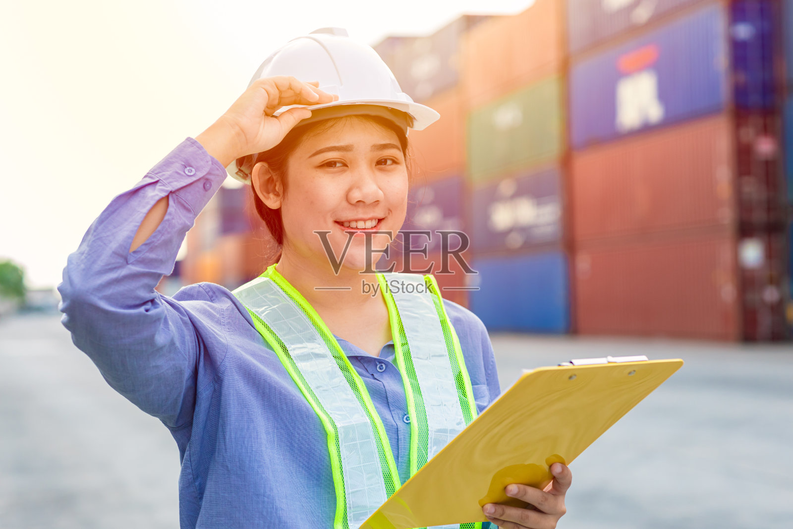 亚洲女孩青少年工人的肖像在航运货物港口进出口工作区域与集装箱箱的背景。照片摄影图片