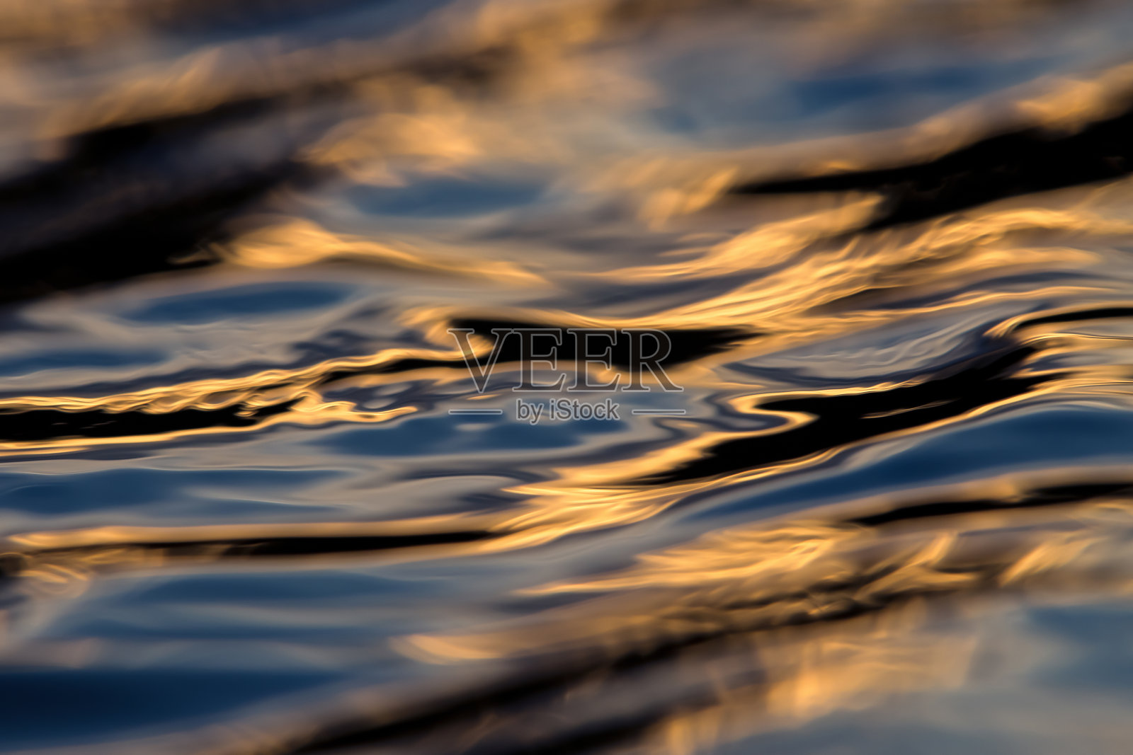 一个美丽的特写，金色和蓝色的水涟漪照片摄影图片