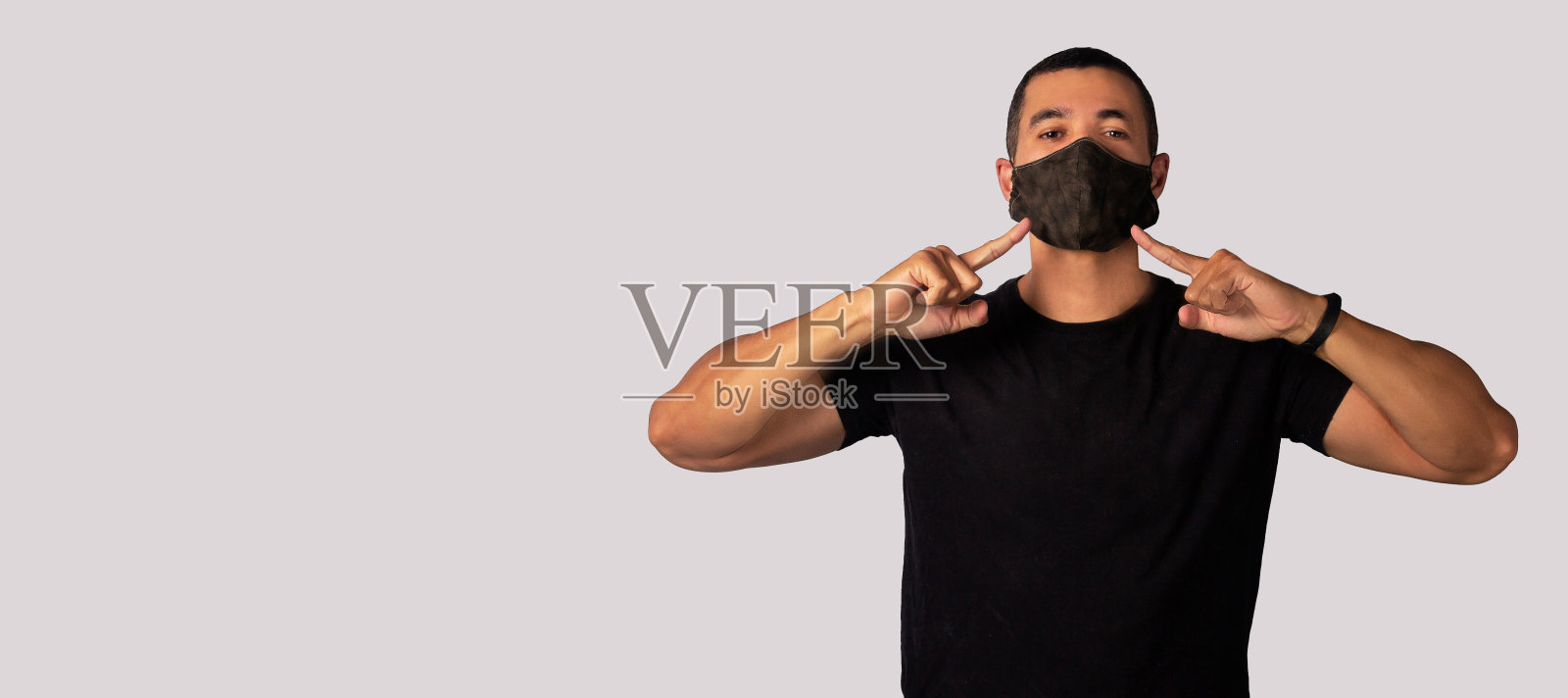 一名成年男子身穿黑色衬衫，戴着N95口罩，以保护自己免受新冠病毒感染。照片摄影图片