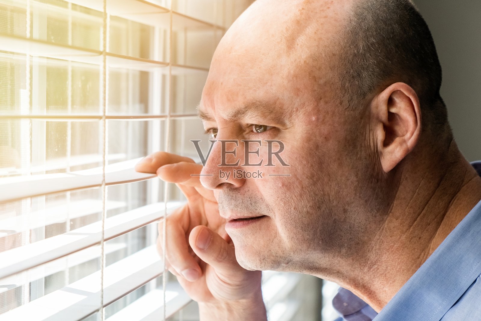 一个成熟的男人从锁着的窗户往里看照片摄影图片