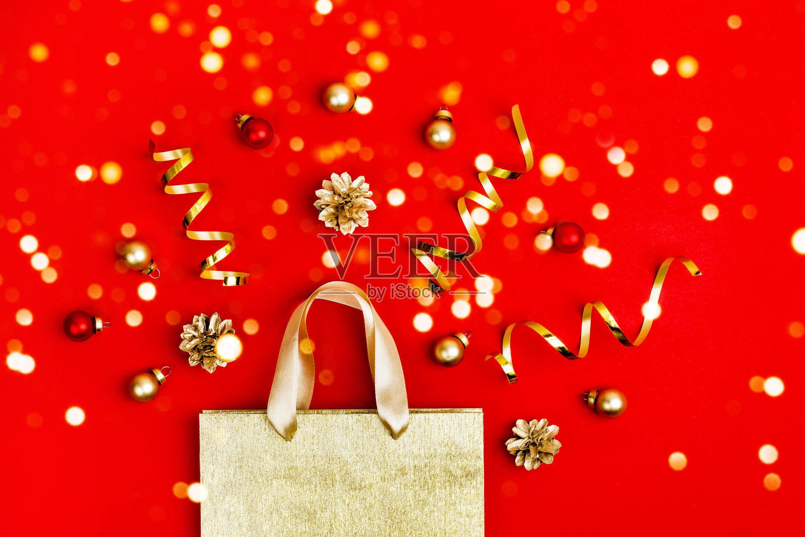 圣诞节销售的概念。金色的购物袋，锥形，蛇蛋白和闪闪发光的灯光在红色的背景照片摄影图片