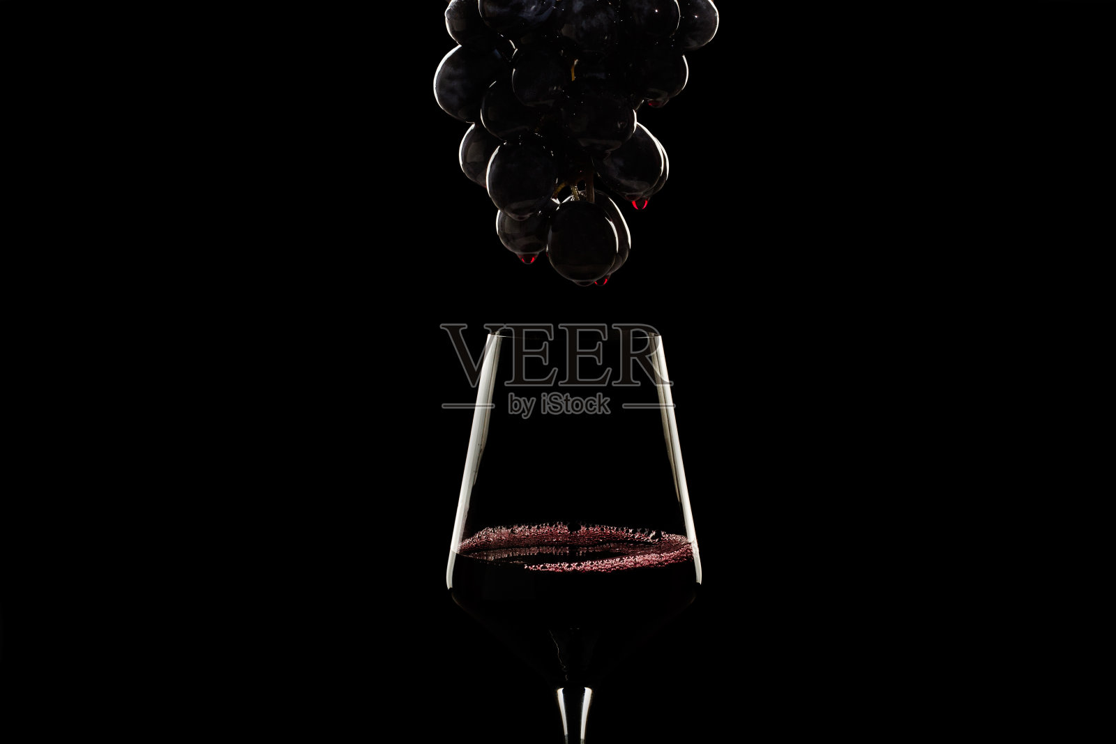 黑葡萄加葡萄酒滴和一杯红酒照片摄影图片