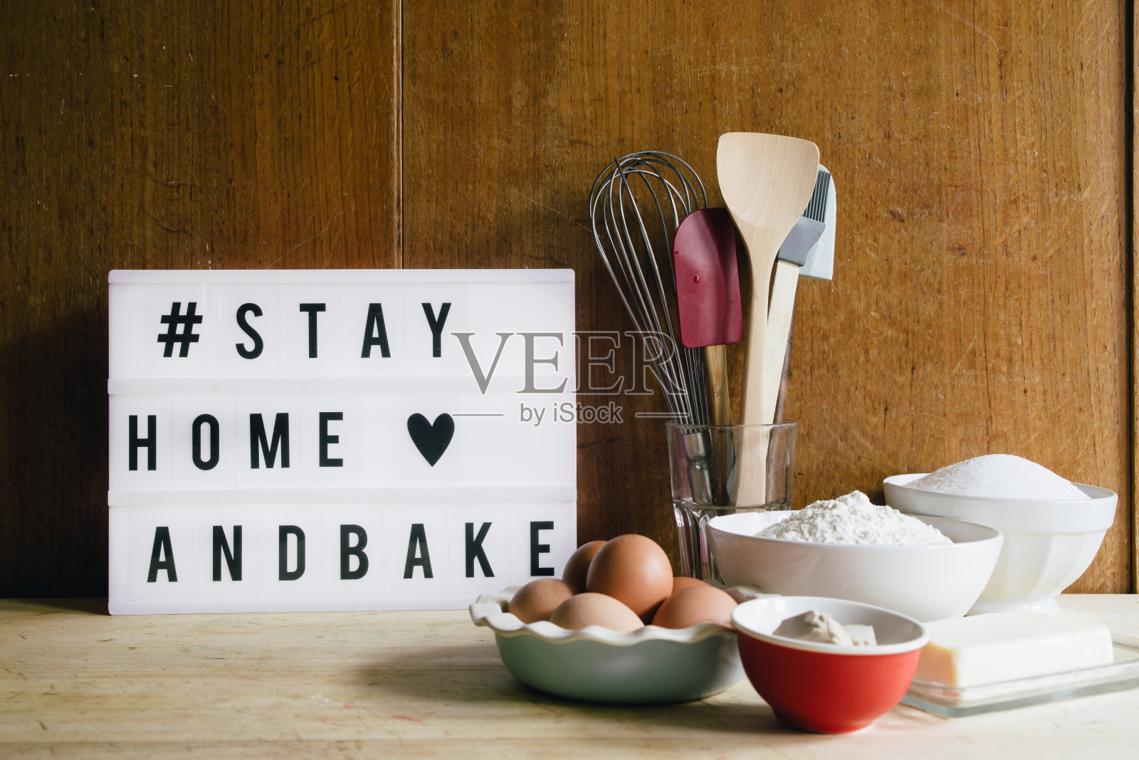 待在家里烤新冠病毒概念图像的冠状病毒大流行，与一个灯箱短信待在家里烤，圈上工具和配料烘焙面包和蛋糕在隔离期间照片摄影图片