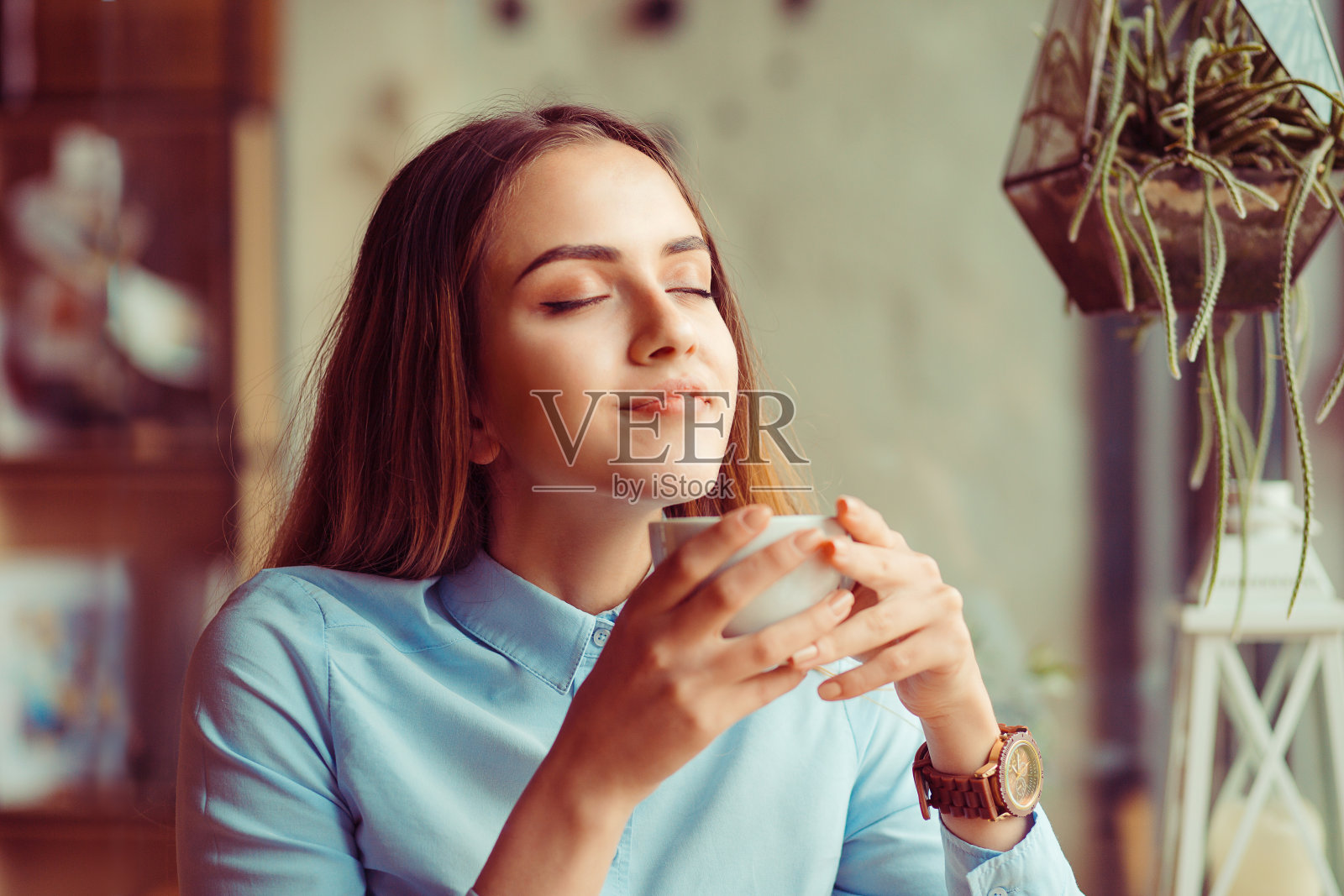 女人享受着她那杯咖啡茶，闭着眼睛喝着热饮照片摄影图片
