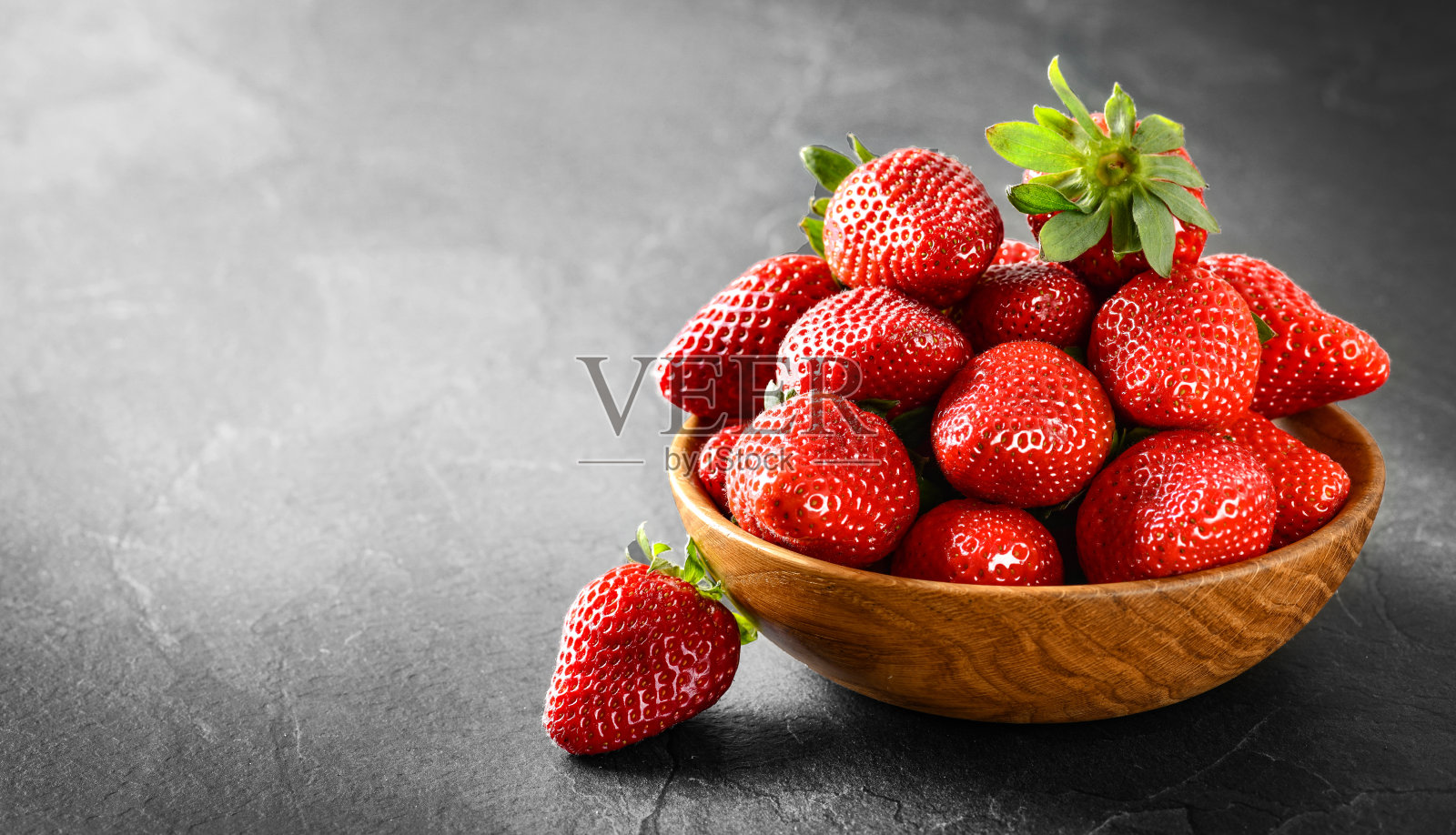 新鲜美丽的草莓在木碗侧视图。照片摄影图片