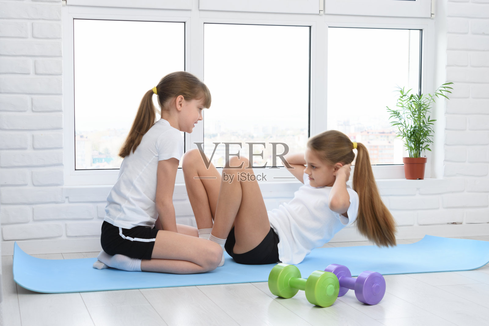 一个女孩帮另一个女孩做腹肌锻炼照片摄影图片