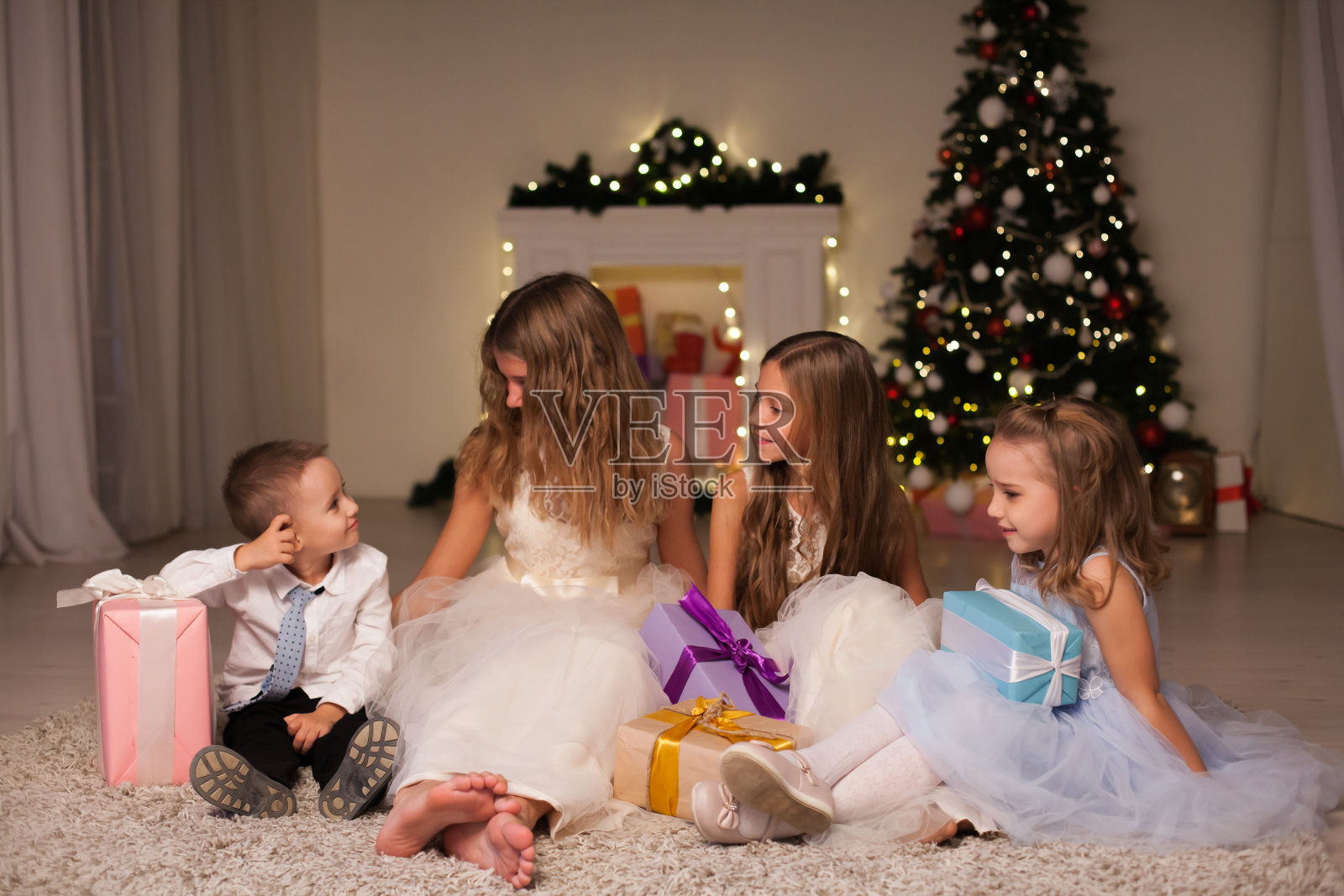 孩子们一家人在新年的圣诞树上打开礼物照片摄影图片