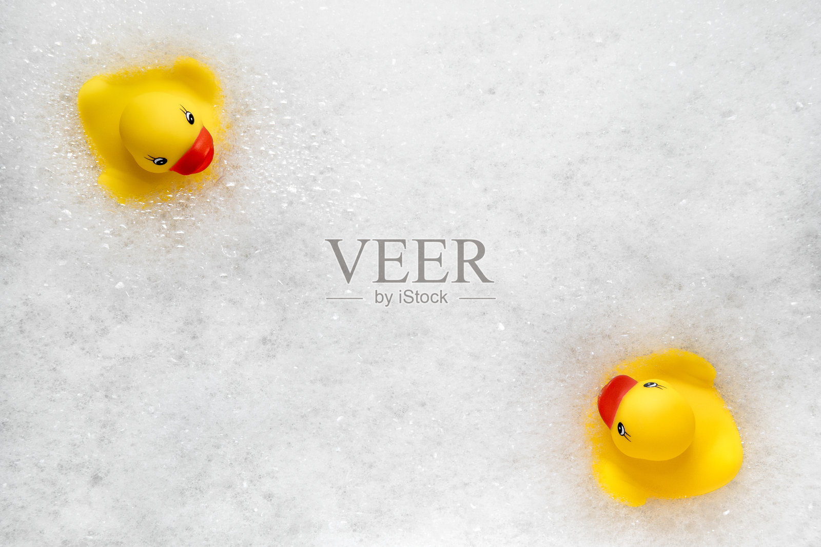 黄橡皮鸭在泡沫水中游泳的高角度视图。黄色的橡胶小鸭在肥皂泡沫，有趣的孩子。照片摄影图片