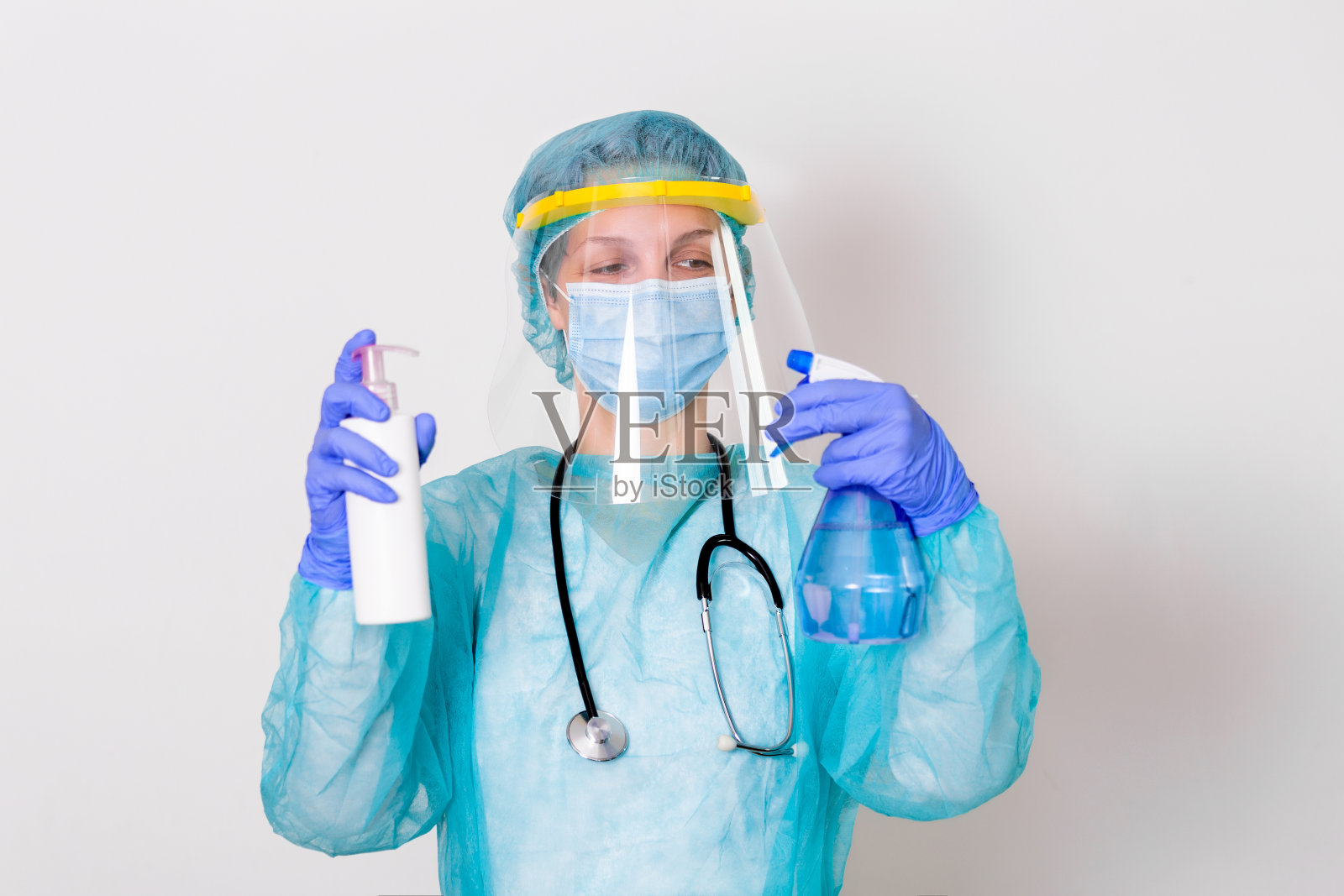 妇女戴手套、生物危害防护服、面罩和口罩，用洗手液瓶和消毒凝胶。冠状病毒或Covid-19防护。照片摄影图片
