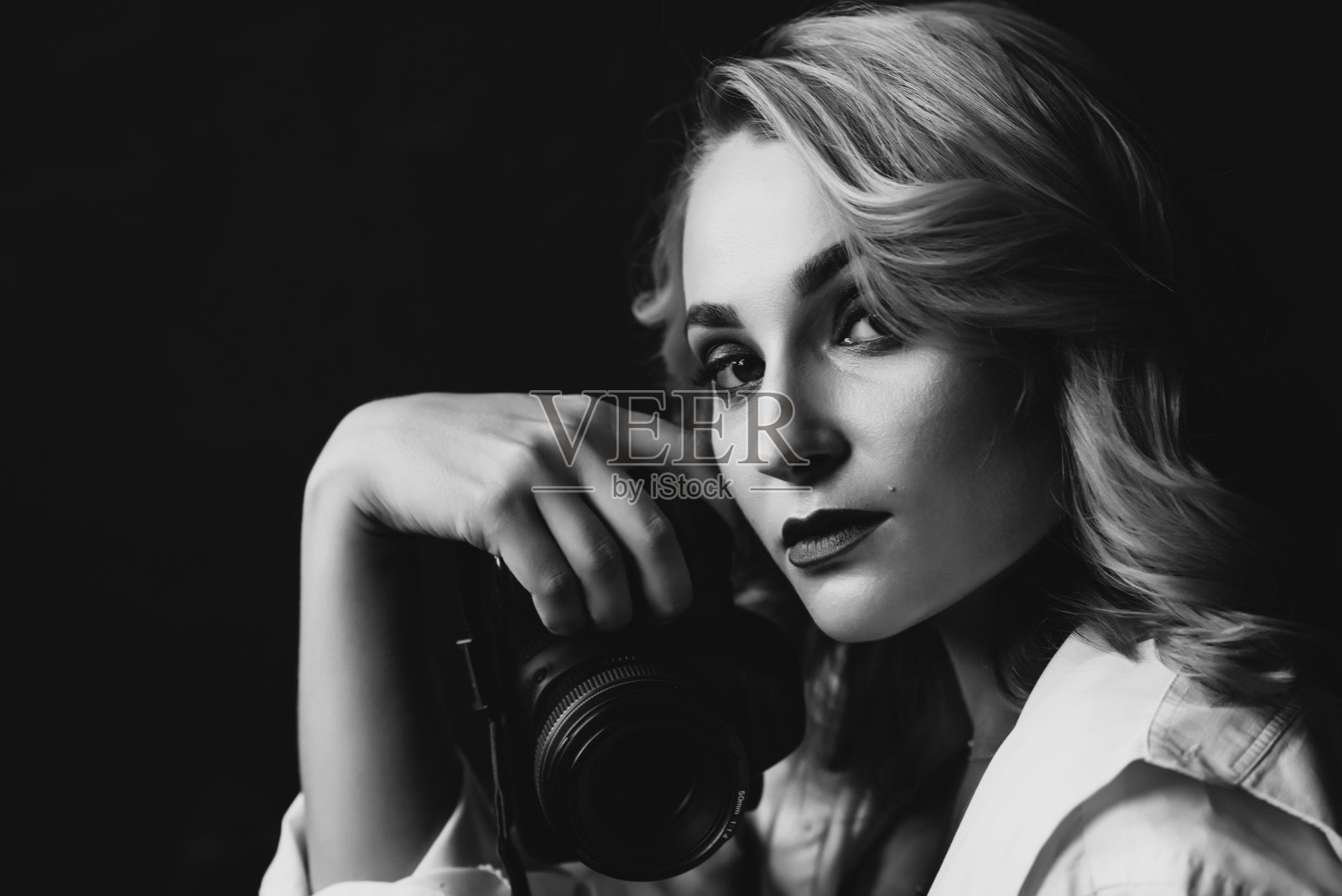 一个美丽的女性摄影师的肖像与相机在她的手在低的关键。黑白艺术照片。软选择聚焦。照片摄影图片