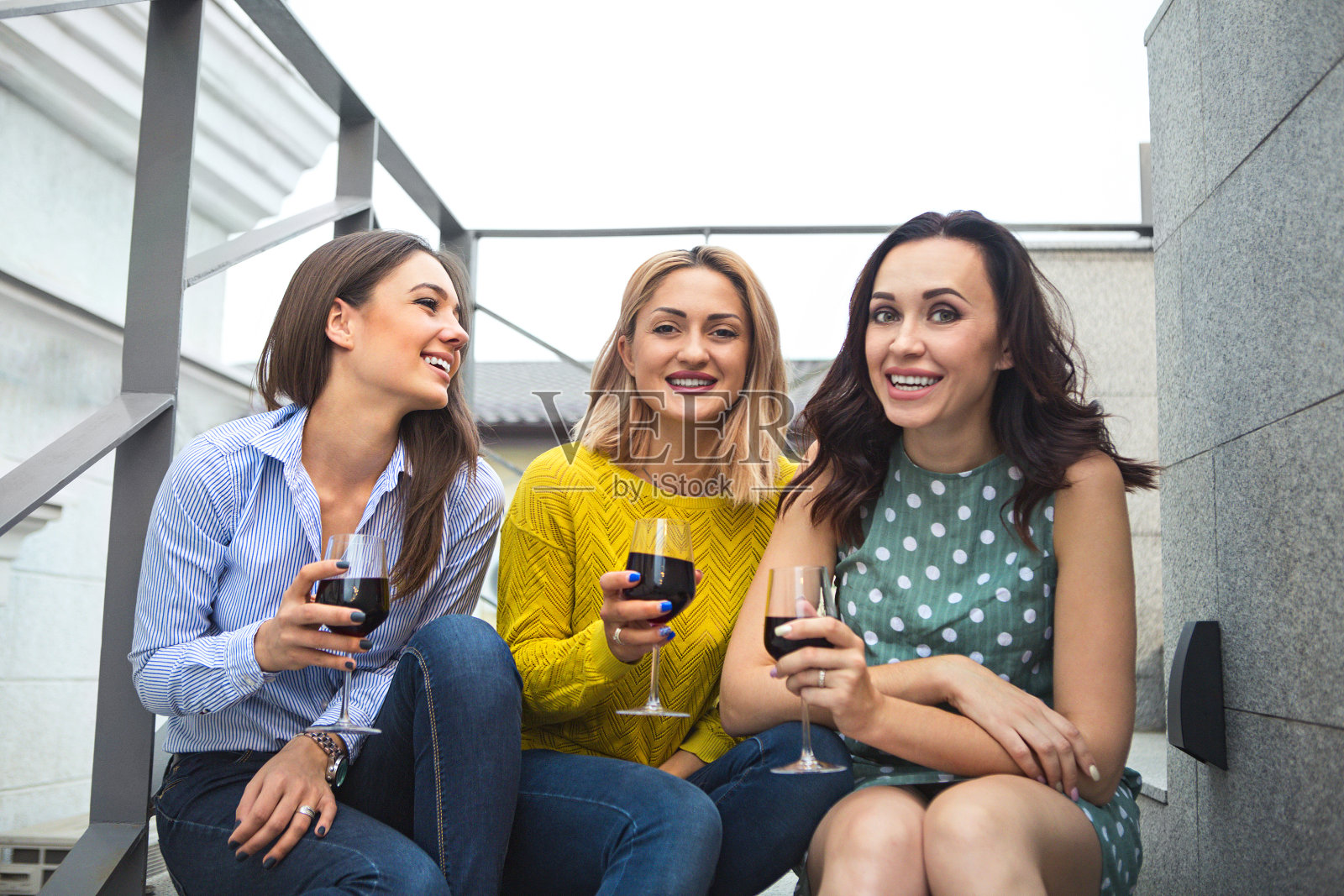 三个年轻快乐的女人笑着，喝着红酒，玩着照片摄影图片