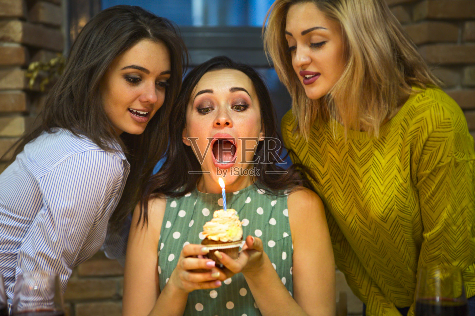 快乐的年轻女子的肖像，抱着生日纸杯蛋糕周围的朋友照片摄影图片