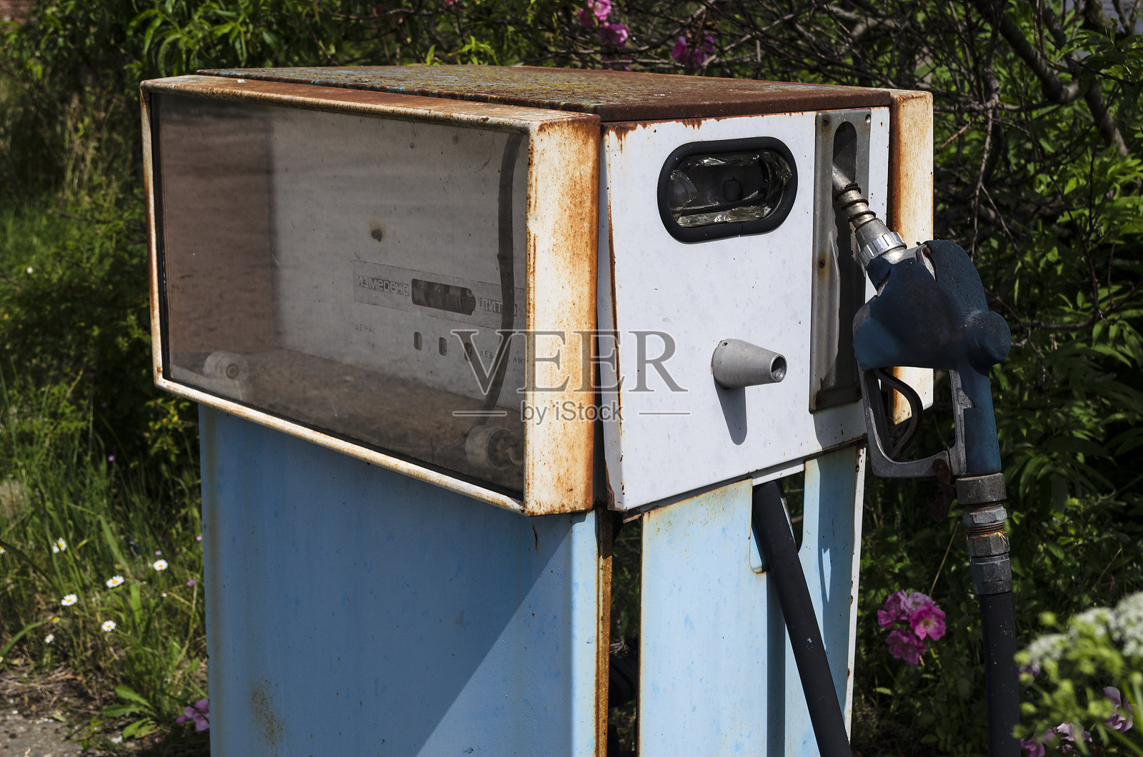 废弃加油站前的一个生锈的老式油泵照片摄影图片