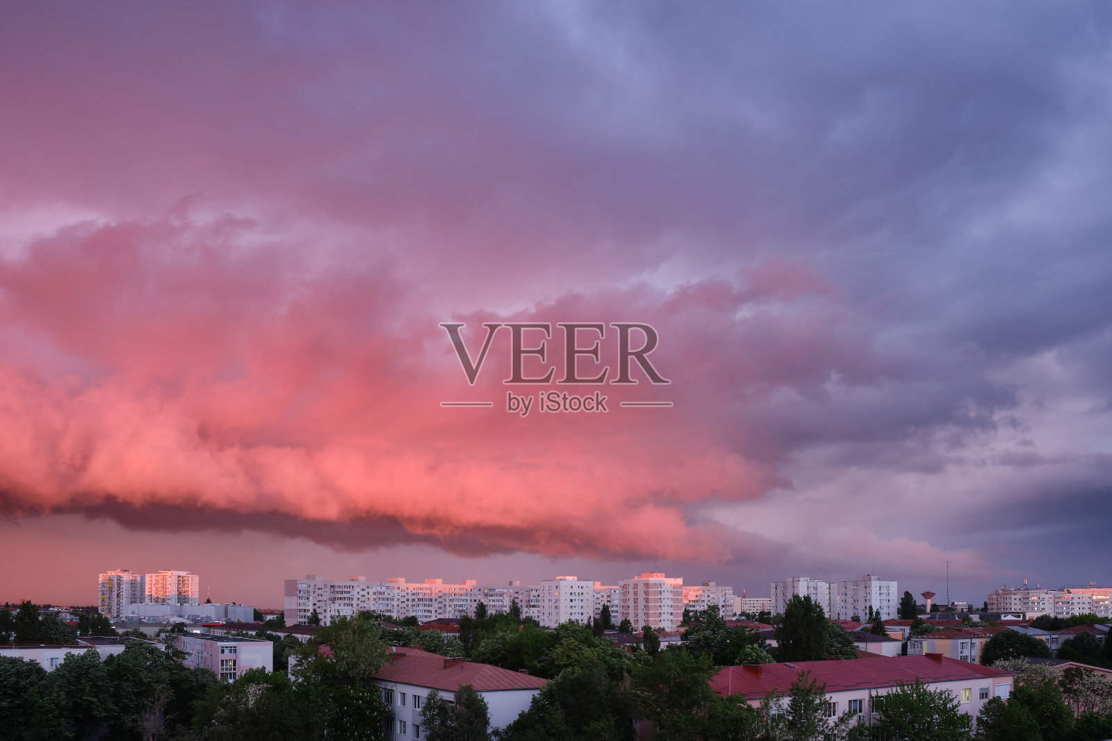 在罗马尼亚的布加勒斯特，日落时的粉色和紫色的暴风云与明亮的建筑物形成了鲜明的对比。照片摄影图片