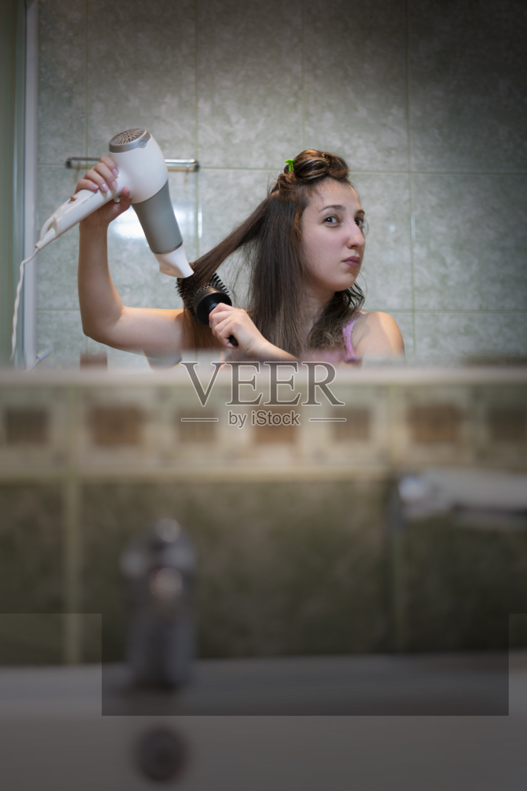 黑发女孩在浴室的镜子前吹干头发照片摄影图片
