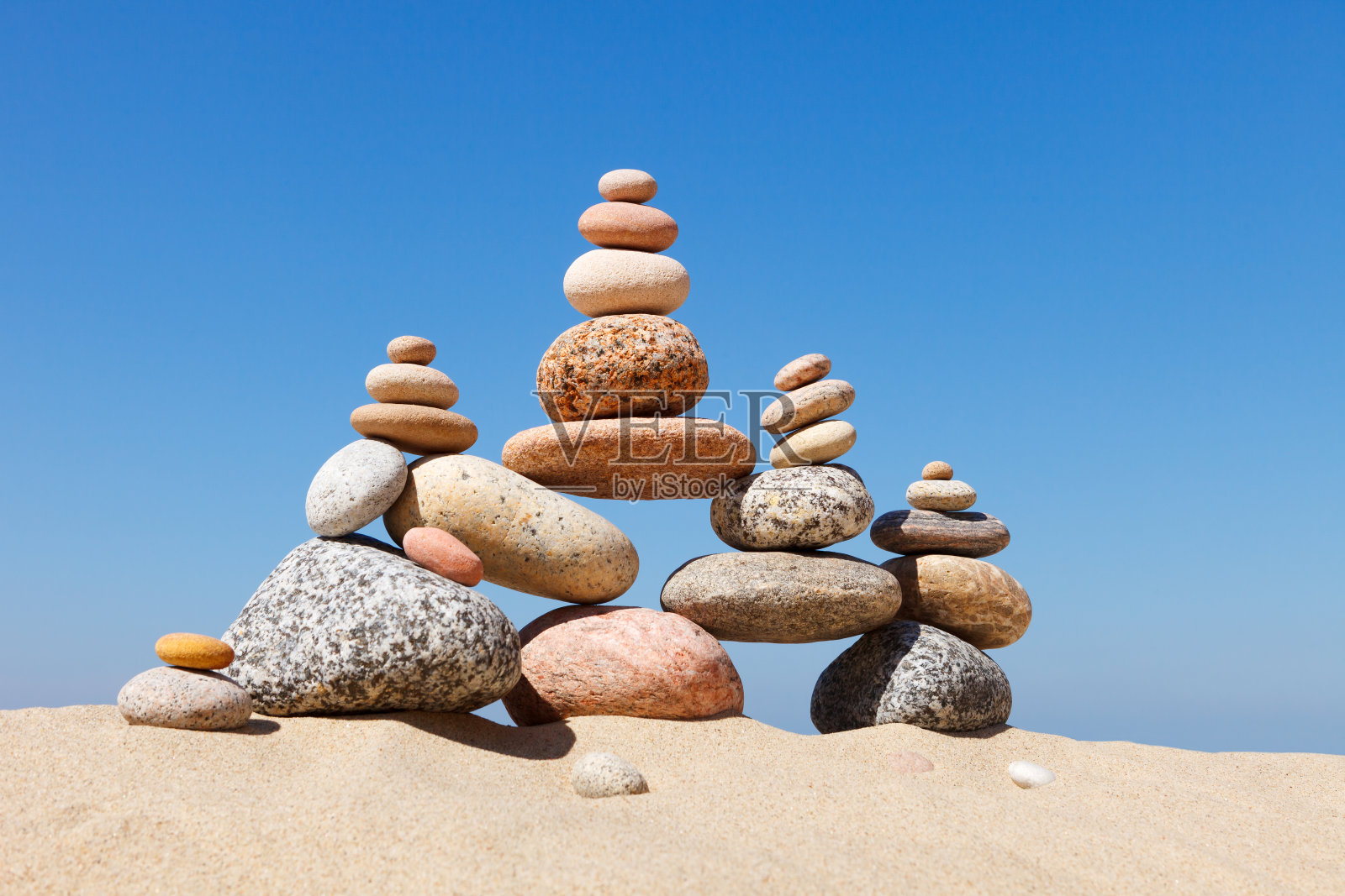 岩石禅宗金字塔的彩色卵石在沙滩上。平衡，和谐和冥想的概念。照片摄影图片