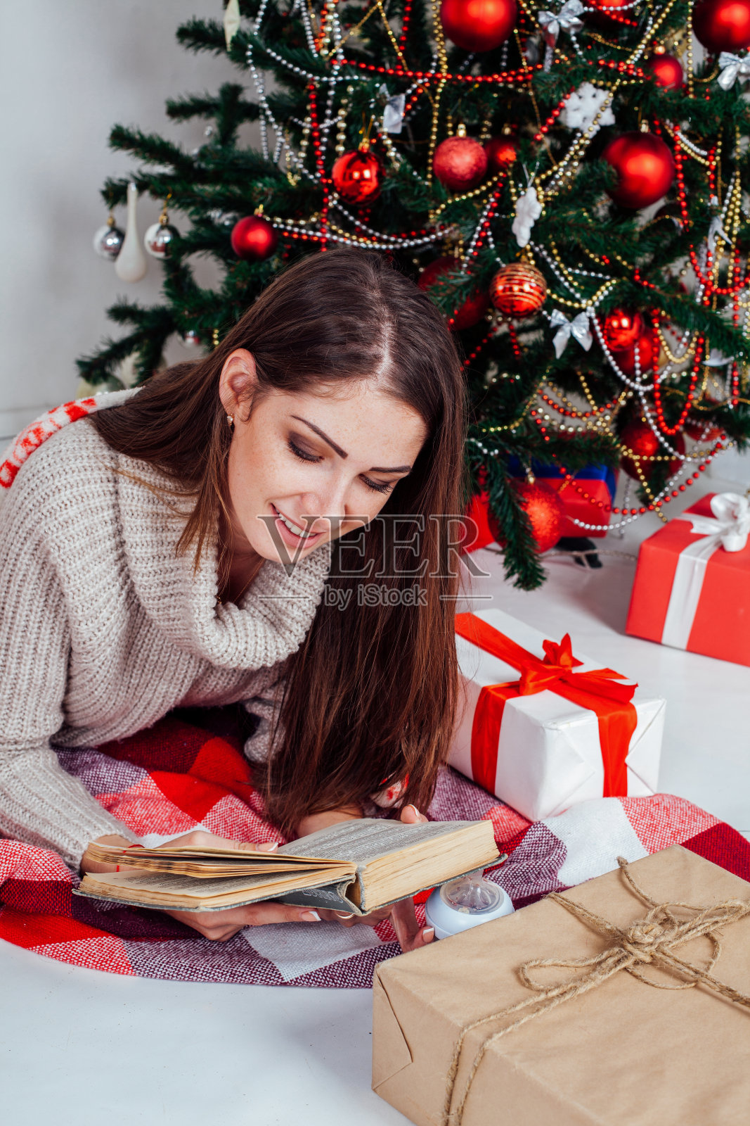 小女孩在圣诞树旁看书，准备圣诞礼物照片摄影图片