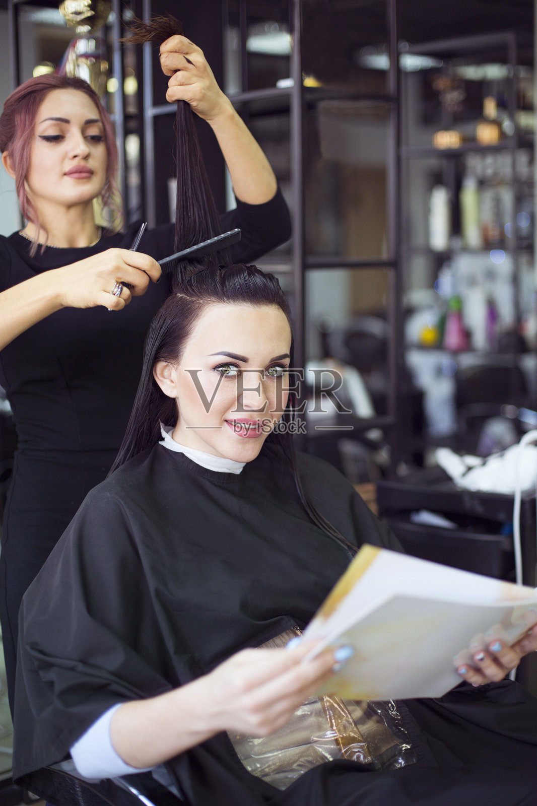 专业发型师准备给她的美丽开朗的女性客户理发梳理她的头发照片摄影图片