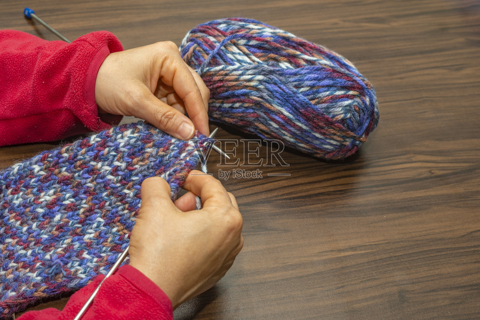 一位中年妇女正在家里用彩绳编织。照片摄影图片