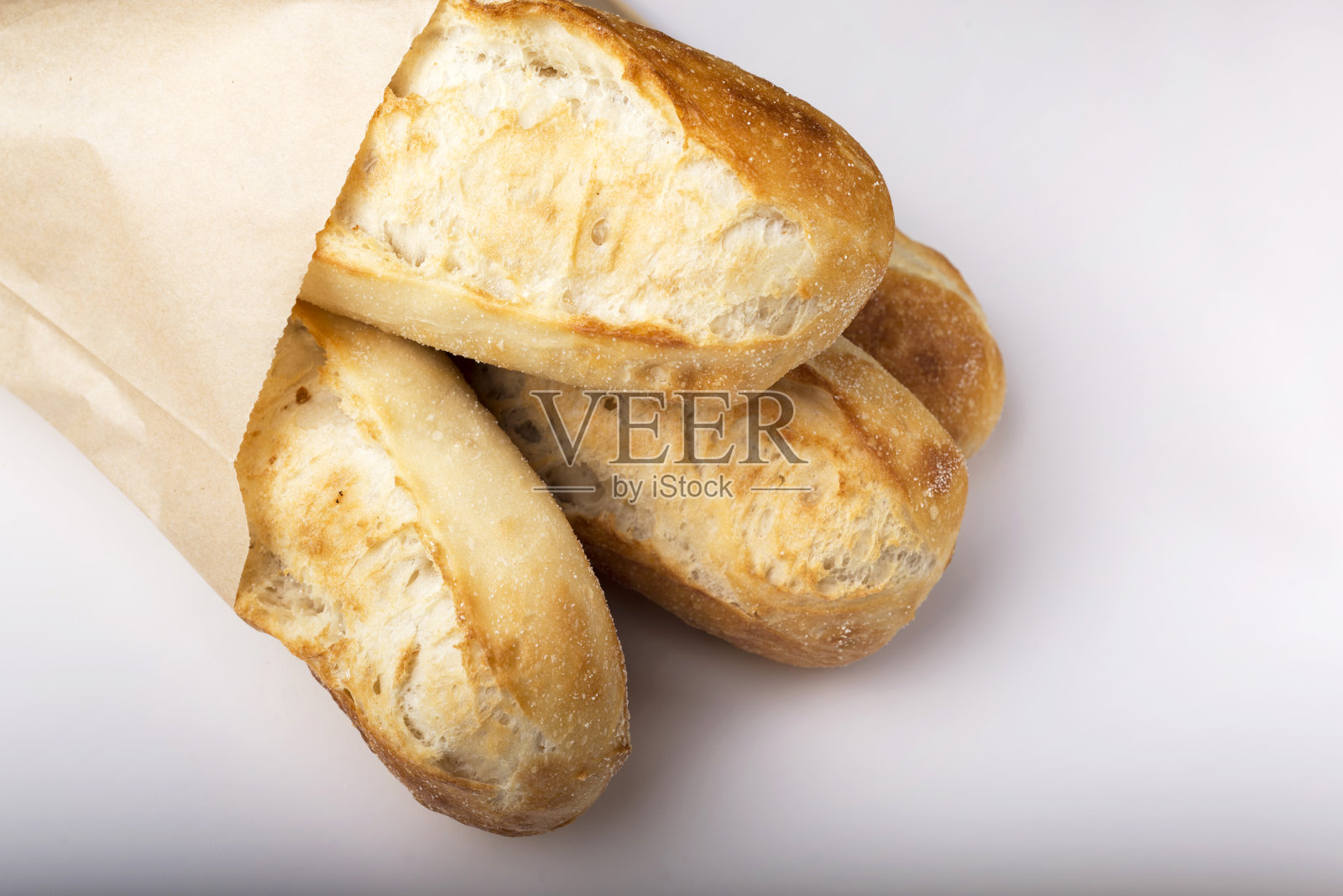 法国长棍面包在纸袋孤立在光的背景。照片摄影图片