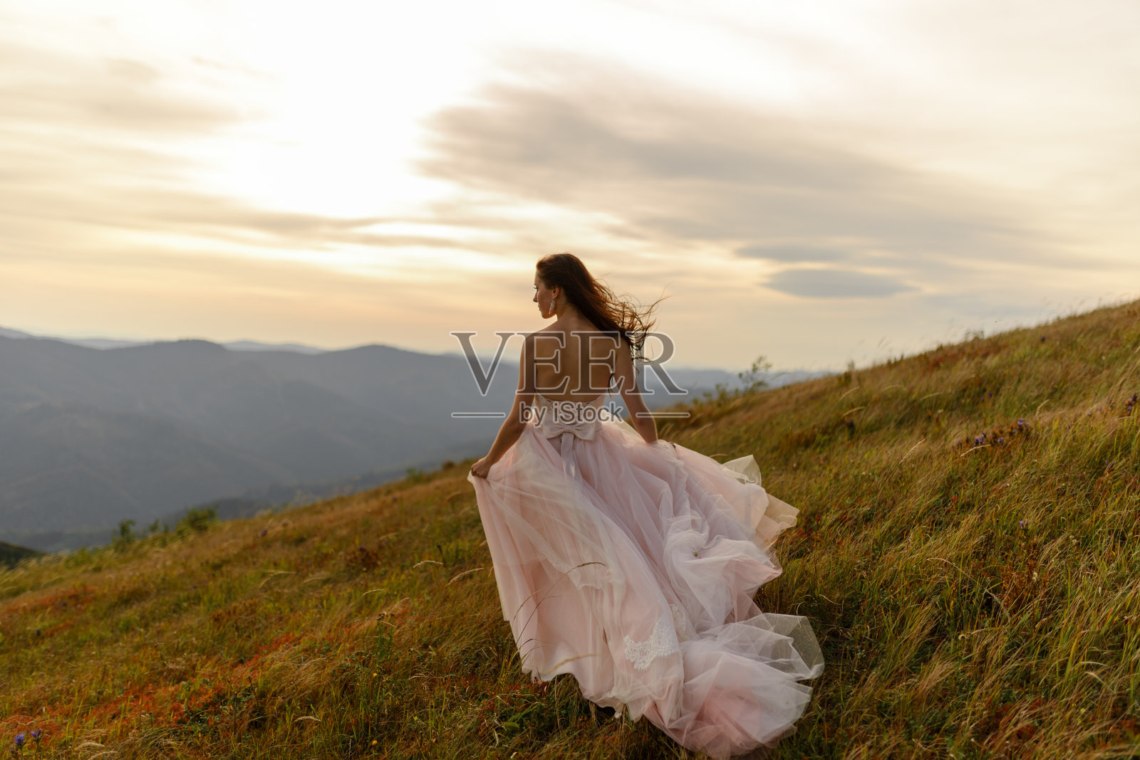 一个美丽的新娘的肖像在一个秋天的山的背景。一阵强风吹着她的头发和衣服。在山顶举行婚礼。自由空间。照片摄影图片