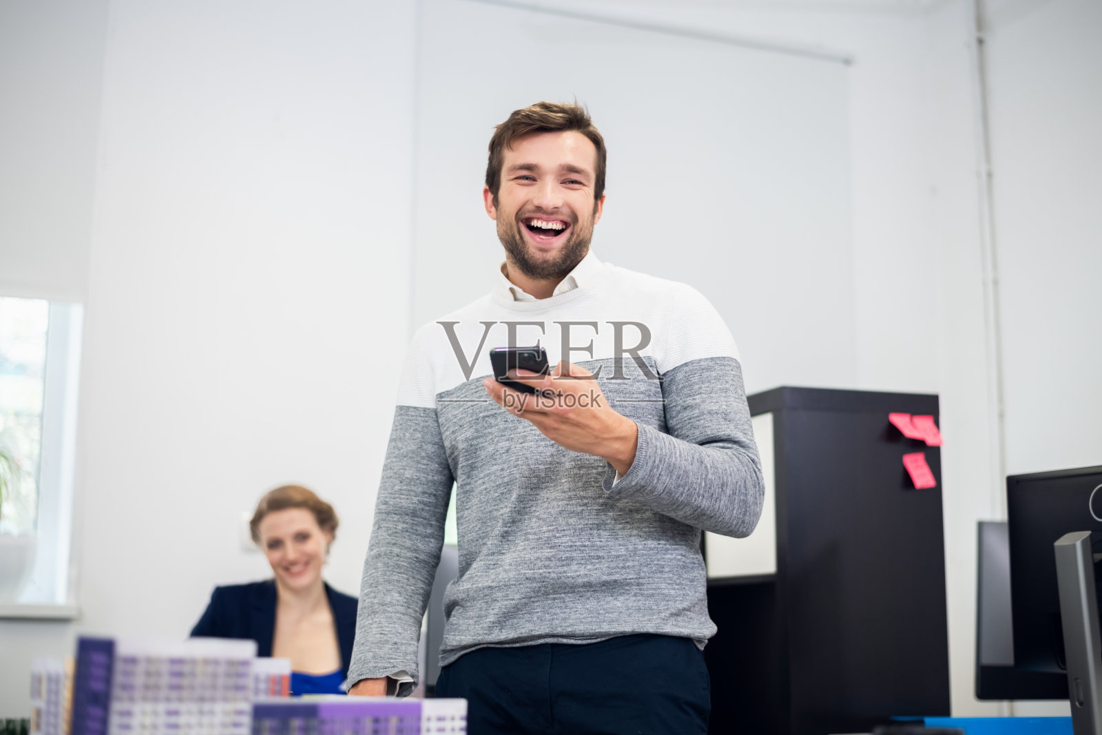 一幅年轻英俊的胡须男子在办公室里大笑的肖像照片摄影图片