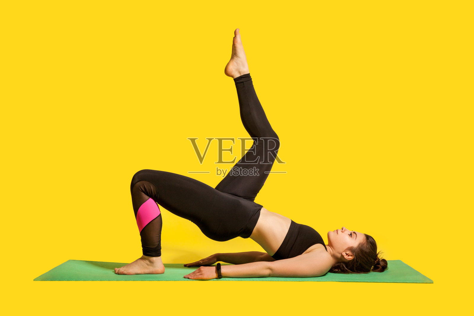 健身女孩穿着紧身运动服练习瑜伽，做单腿桥式抬腿，锻炼肌肉照片摄影图片