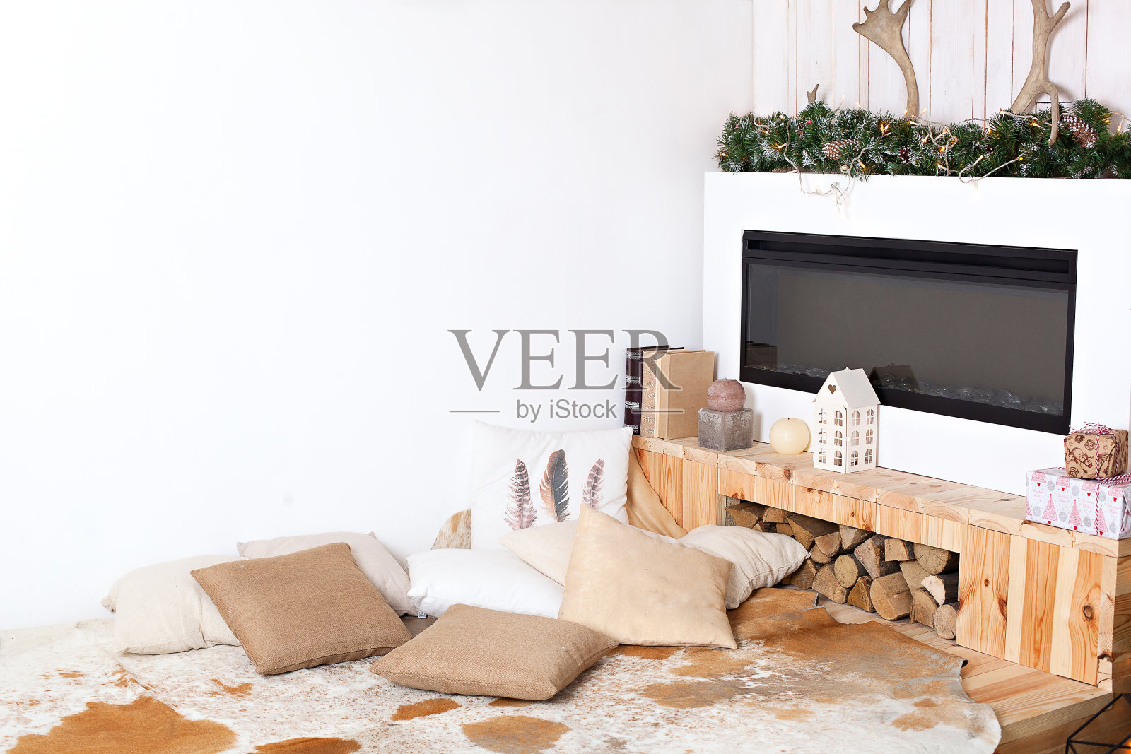 时尚的圣诞节斯堪的纳维亚简约室内与优雅的沙发。舒适的家。现代乡村住宅内饰有木床、柴火、壁炉。圣诞节装饰在一个房间的家。新的一年照片摄影图片