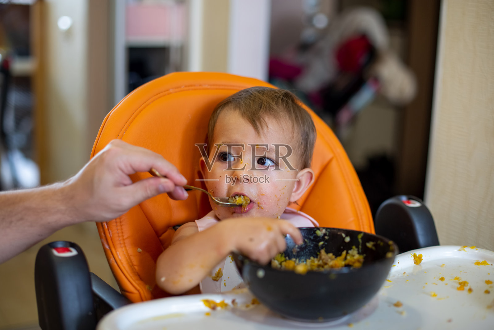 递上一个盘子，用父母拿着的勺子吃。特写，前视图，软焦点，模糊背景照片摄影图片