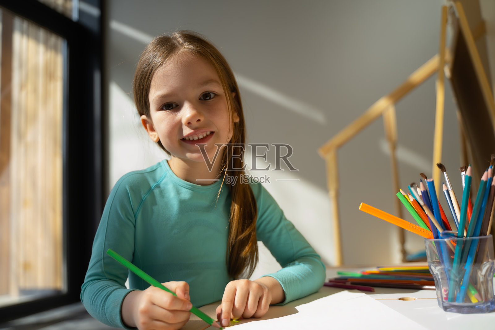 快乐的小女孩在家里用彩色铅笔画画照片摄影图片