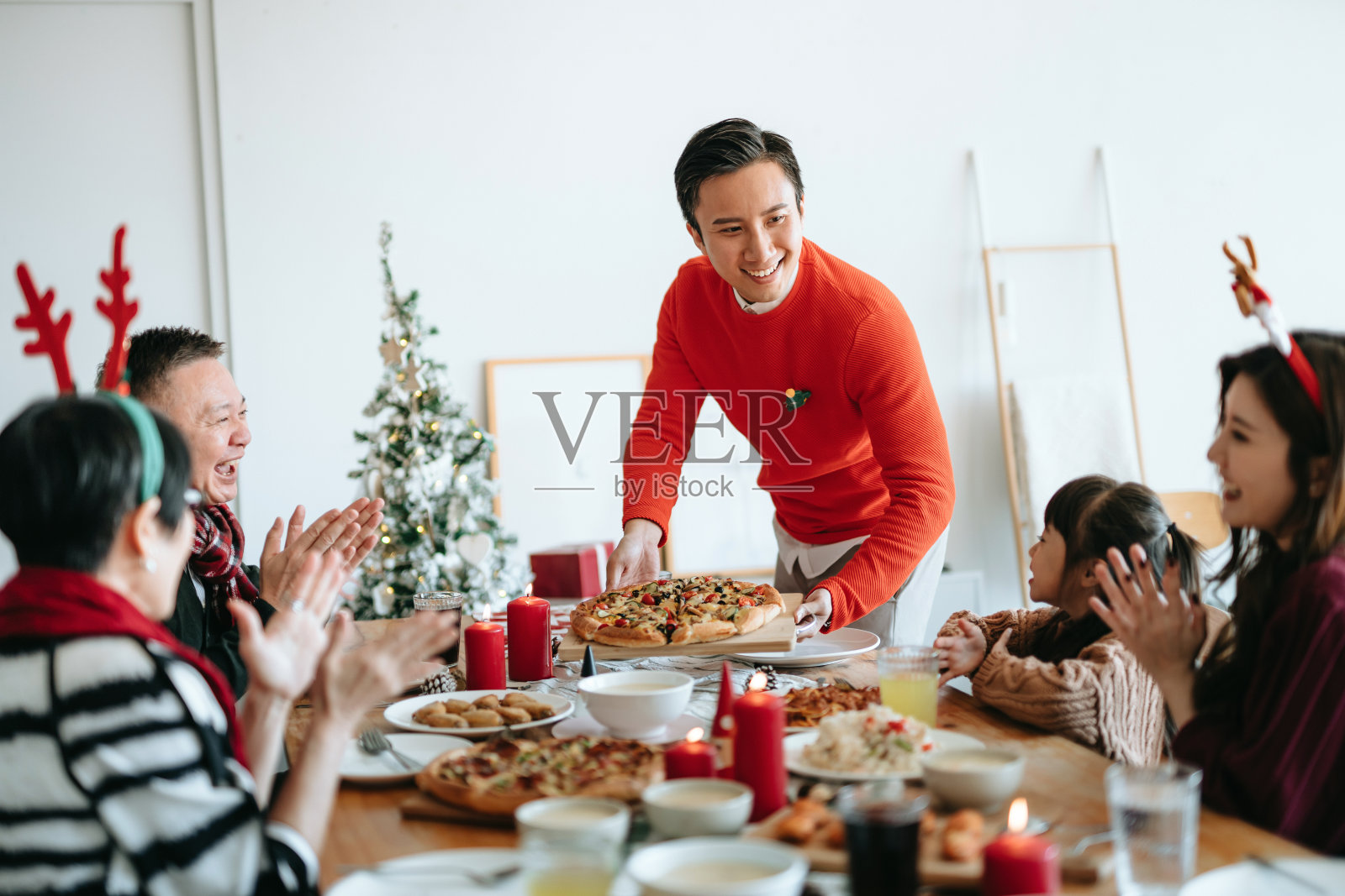 快乐的亚洲多代家庭花时间一起庆祝圣诞节，微笑的年轻人在圣诞派对期间在家里为家人服务食物照片摄影图片