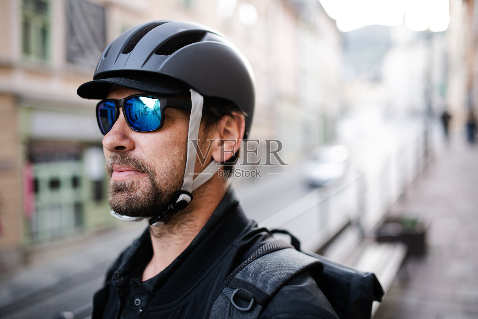 戴着自行车头盔和太阳镜的快递员。照片摄影图片