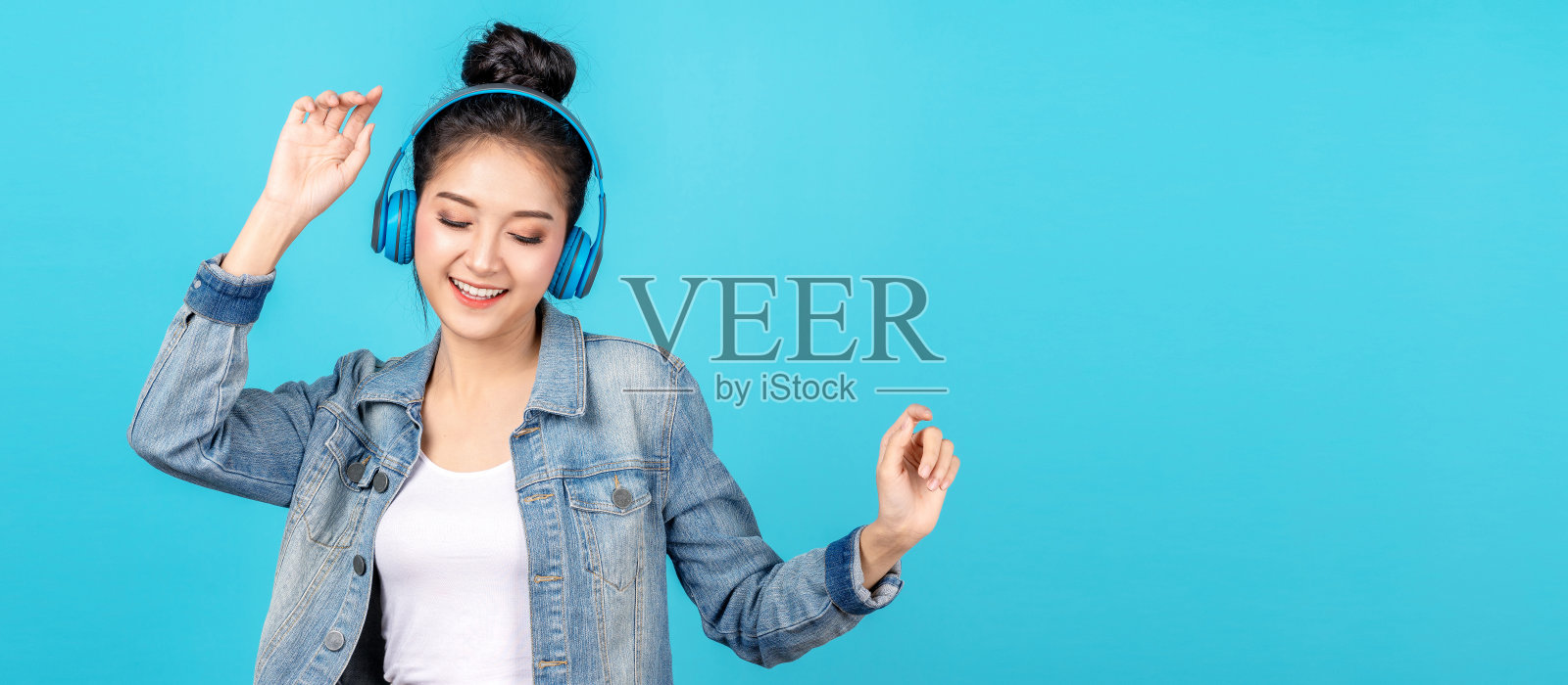 年轻快乐有魅力的亚洲女人用耳机享受听歌曲的概念下正常的生活，消遣或爱好网上。检疫活动亚洲生活方式，听音乐在网上电台。照片摄影图片