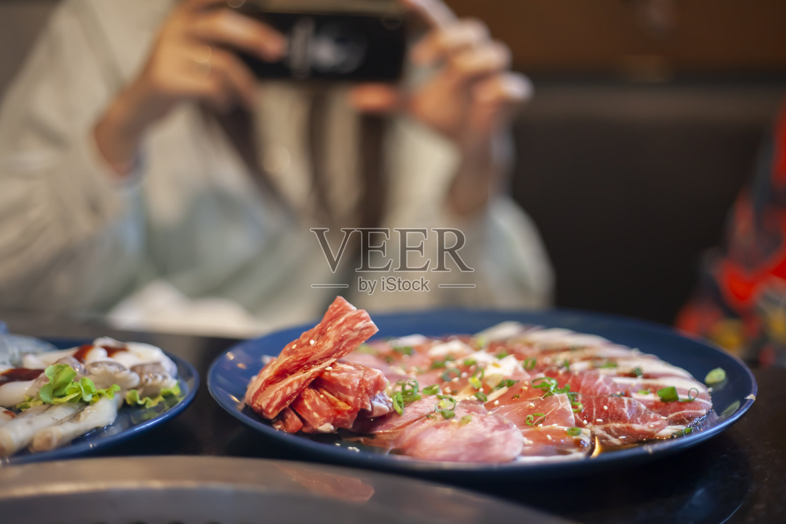一个女人在餐厅用手机拍食物照片照片摄影图片
