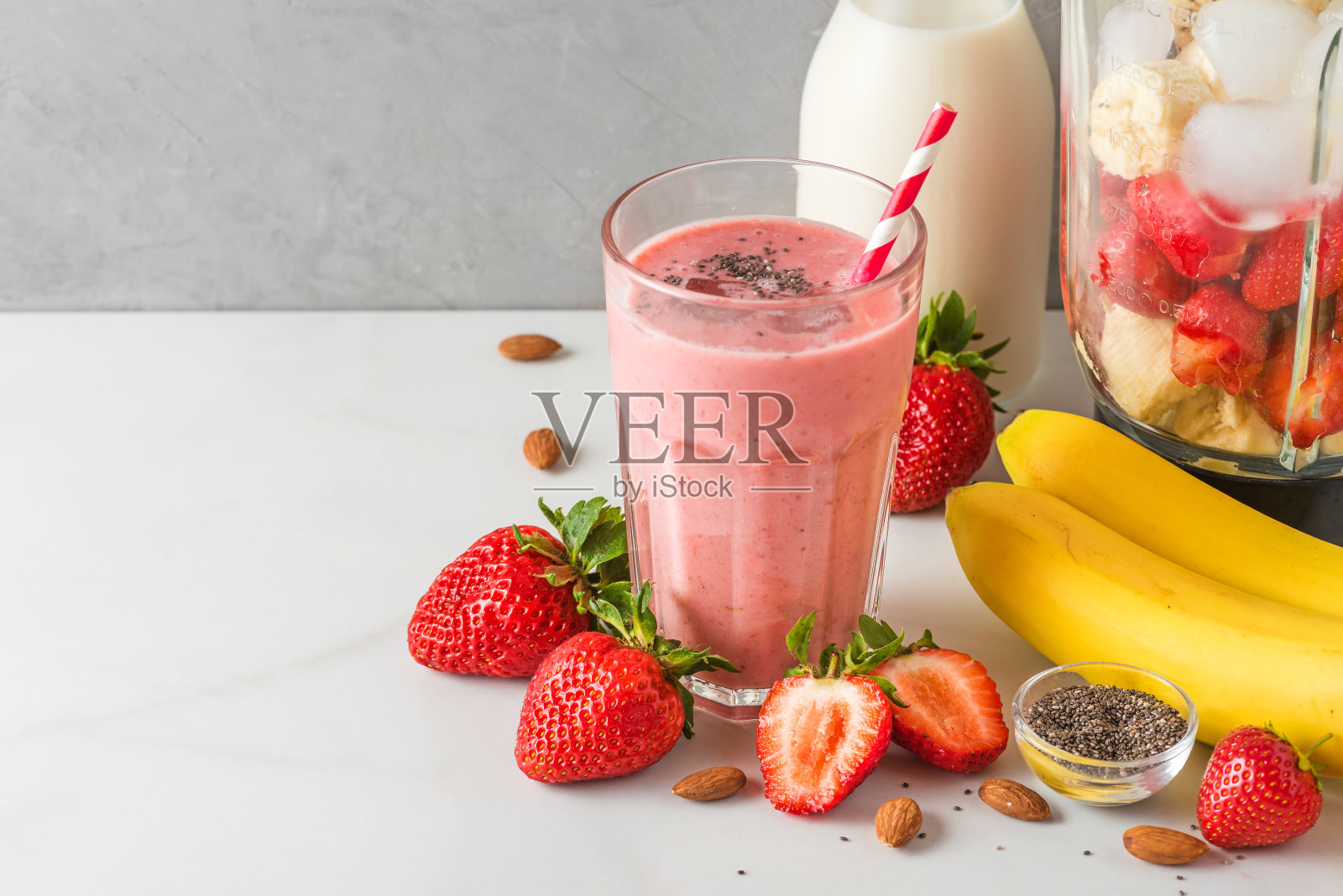 一杯草莓和香蕉纯素奶昔或杏仁牛奶与新鲜多汁的原料在搅拌机照片摄影图片
