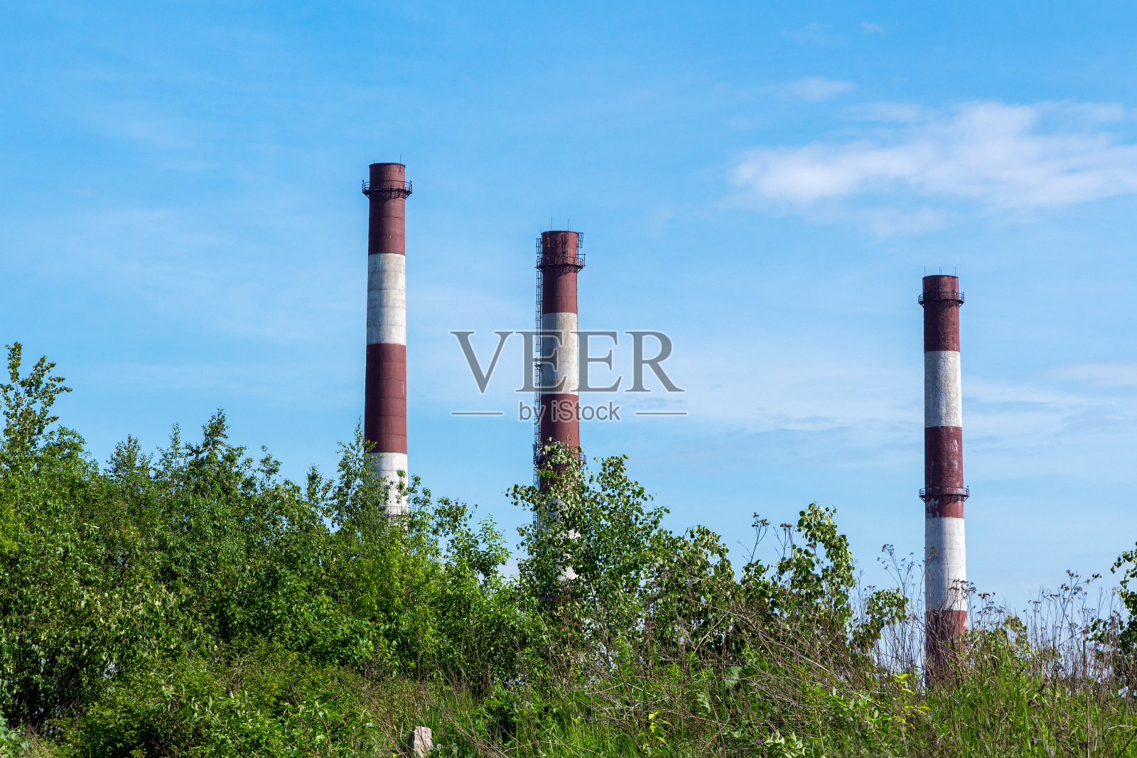 蓝天背景下发电厂的三根高高的管道照片摄影图片