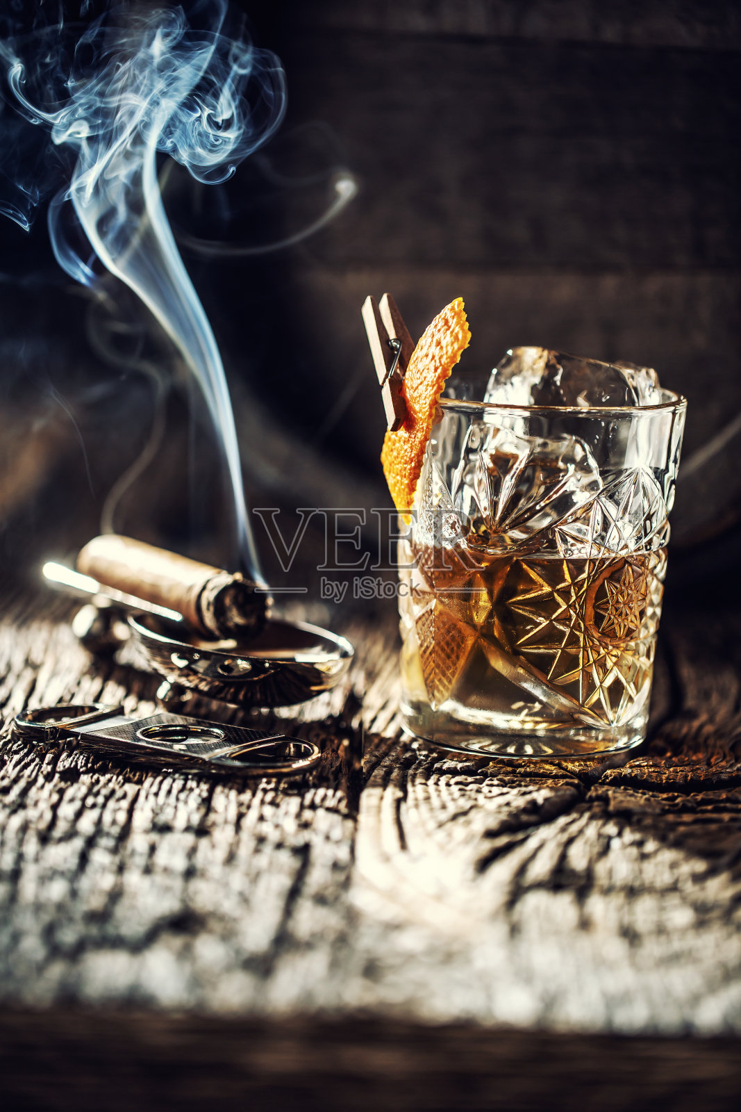 威士忌，不加冰，杯中有燃着的雪茄，背景是一个旧木桶照片摄影图片