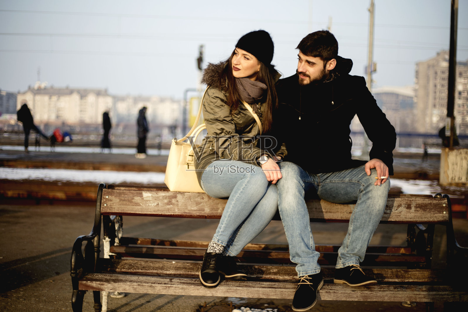 一对情侣坐在火车站的木凳上。一对夫妇坐在站台上等火车。照片摄影图片