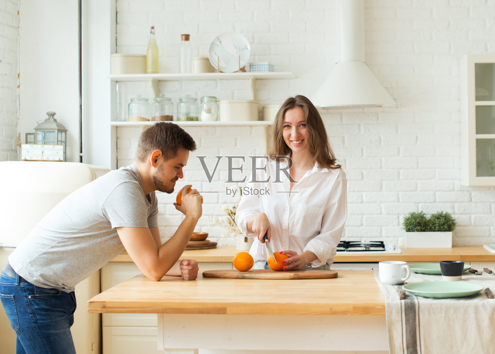 年轻的白人男女，在厨房一起煮橙汁照片摄影图片