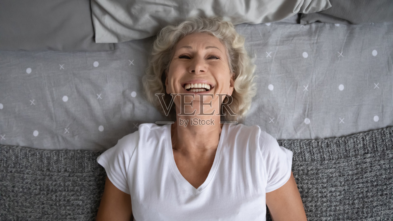 俯视图快乐成熟的女人放松在床上照片摄影图片