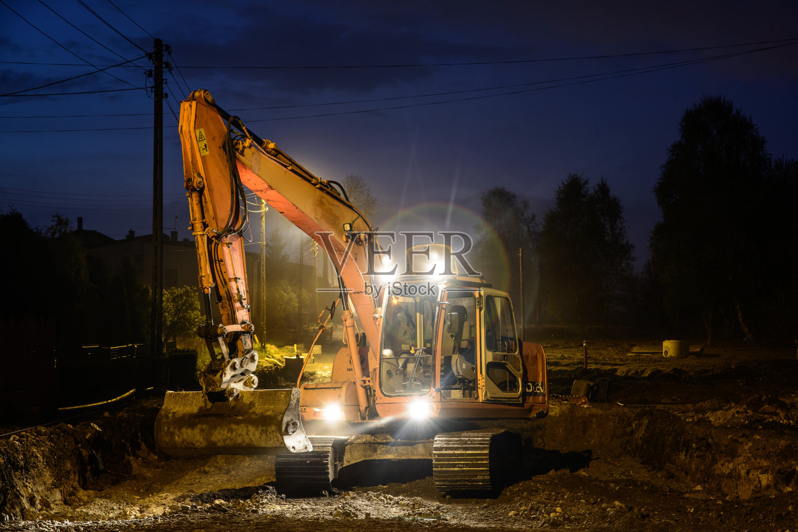 橙色的挖掘机晚上在街上工作照片摄影图片